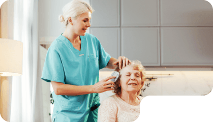 aide combing the hair of the senior woman
