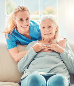 aide smiling while hugging the senior woman