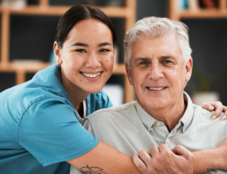 a smiling caregiver standing behind a seated elderly man