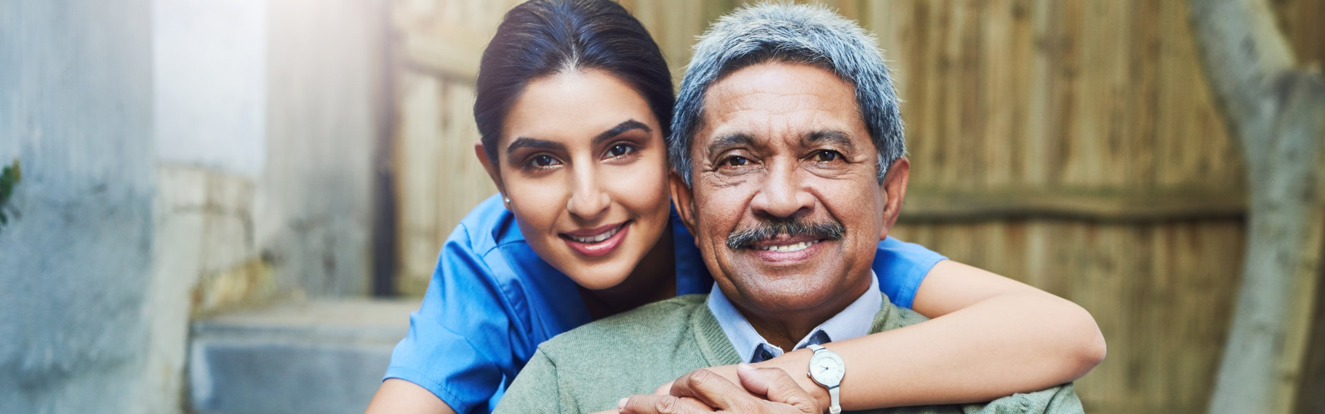 a woman hugging an elderly man outdoor